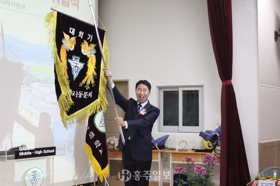 총동문회기 인계인수를 하고 있는 김재원 취임회장이 '갈산중학교 화이팅!'을 외치고 있다.