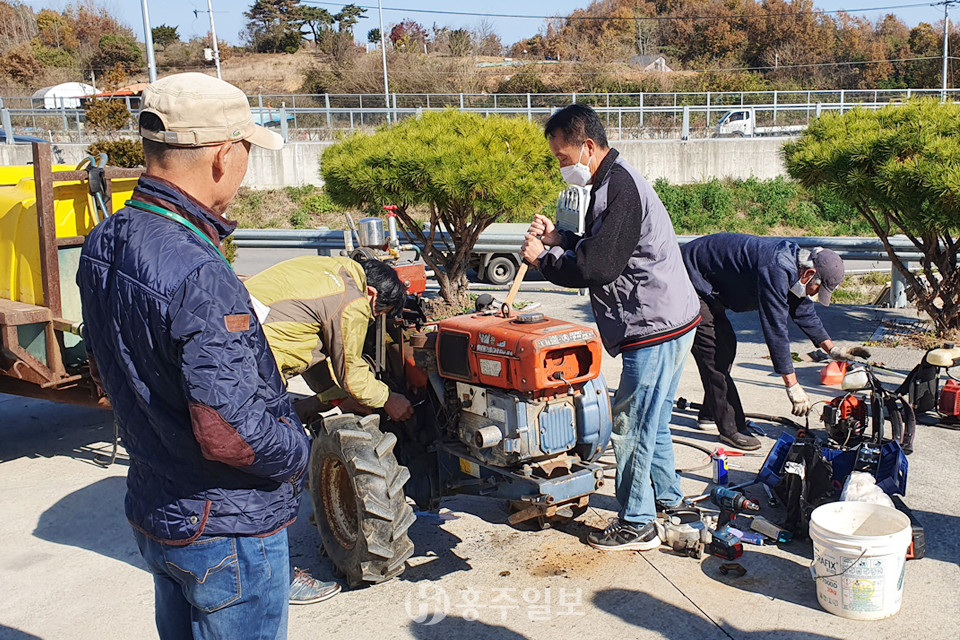 농기계를 수리하고 있는 홍동면 주민자치회 위원들.
