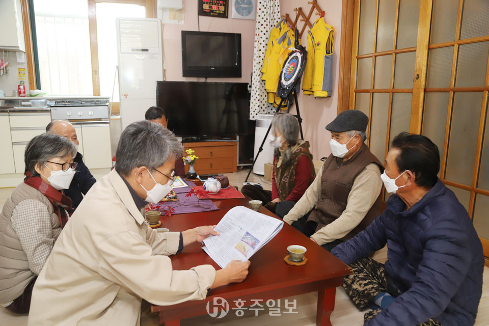 전만성 작가가 장창주 어르신에게 신문에 실린 그림을 보여주고 글을 읽어주는 모습.